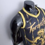 camiseta raptors negra y dorada diseño lateral con borde dorados en cuello y manga